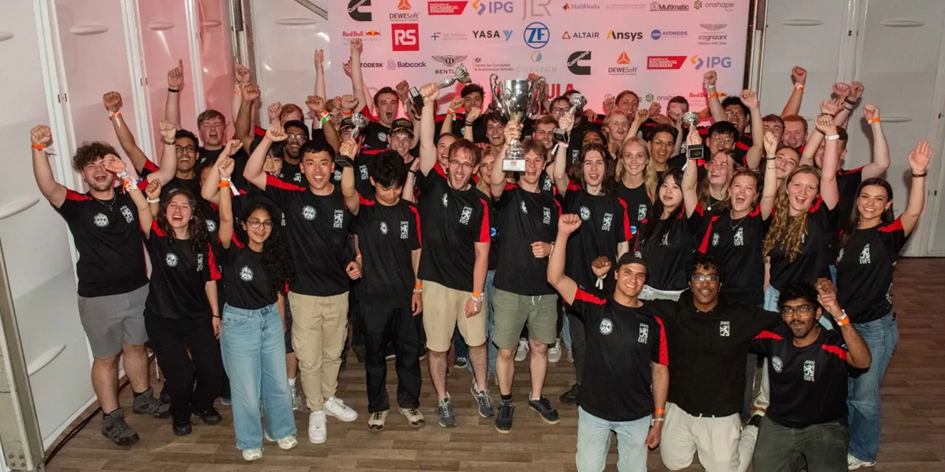 Group of people raising their hands and celebrating with trophies