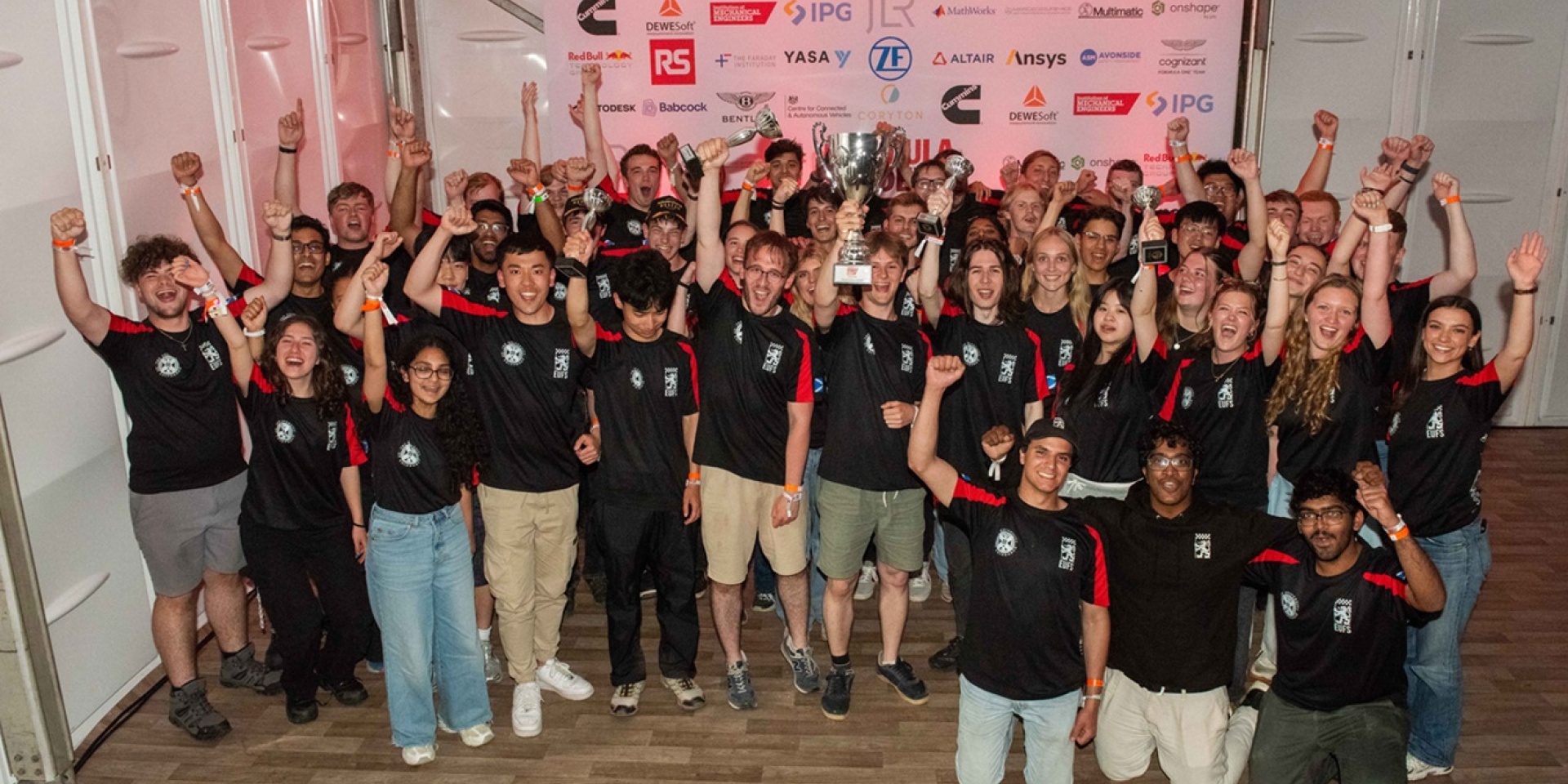 Group of people raising their hands and celebrating with trophies