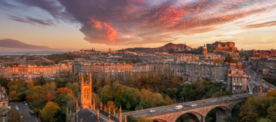 Sunset view of Edinburgh with historic buildings and Edinburgh Castle under colorful clouds