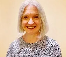 A portrait of a smiling woman with a chin-length grey hair wearing in a patterned top