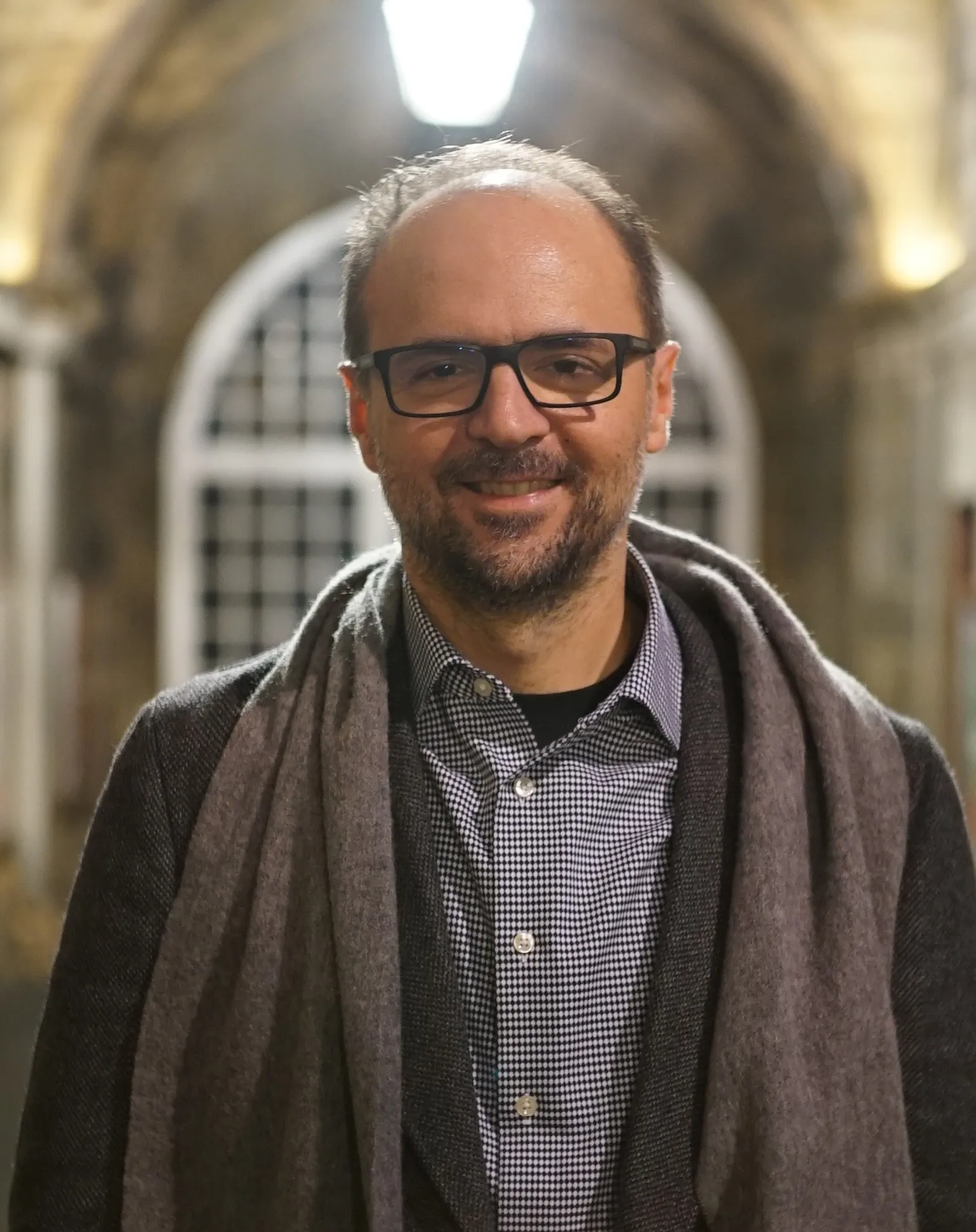 Photo of Aggelos Kiayias wearing a dark coat and grey scarf.