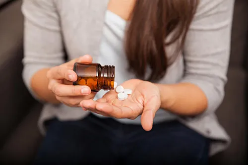 Closeup of a young brunette getting some drugs from a bottle at home