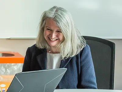 Photograph of Jane Hillston smiling as she looks at a laptop screen