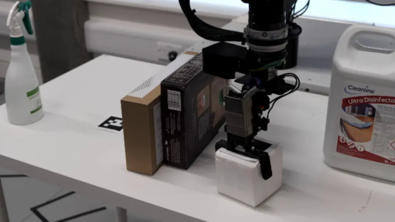 Closeup of the Schunk gripper while robot is picking a box off the table.