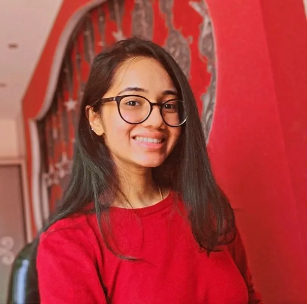 Photo of a young black haired woman wearing glasses and smiling