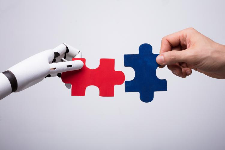 Robot hand and human hand combining two jigsaw pieces