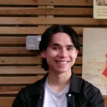 A portrait photo of a young, dark hear man, smiling