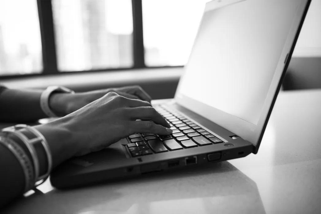 grayscale photography of a woman working in front of laptop