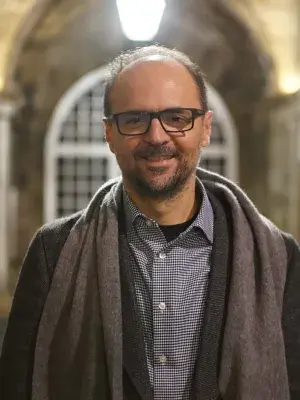 Photo of Aggelos Kiayias wearing a dark coat and grey scarf.